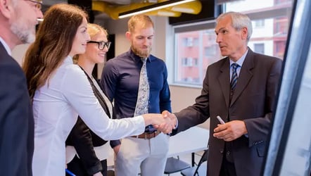 smiling-businesswoman-shaking-hand-with-senior-businessman-board-meeting_23-2147923358.jpg