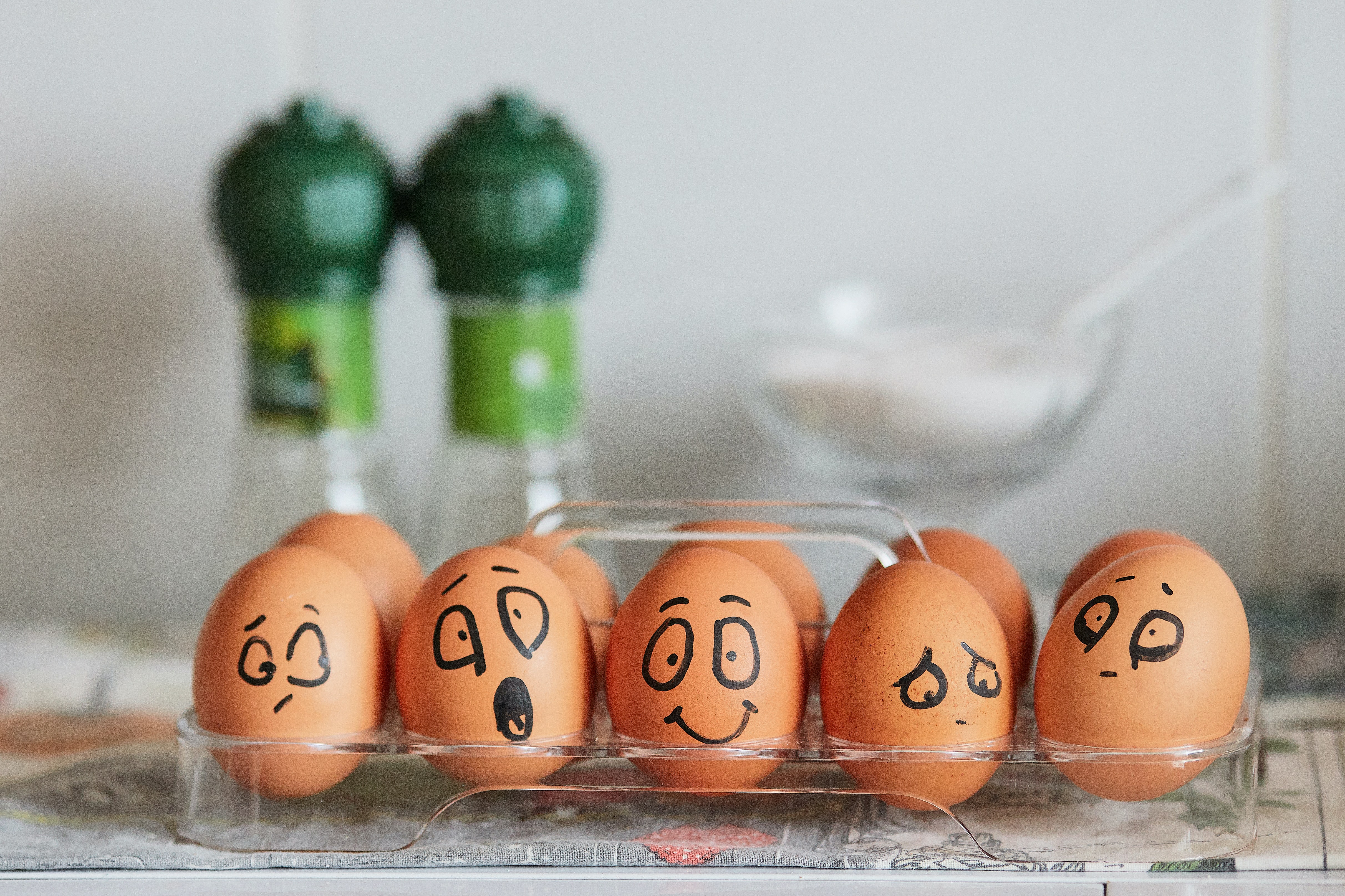 Carton of brown eggs with different emotional faces drawn on them